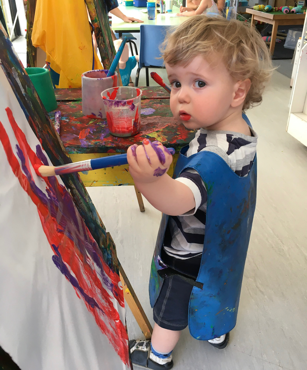 Toddler painting at easel